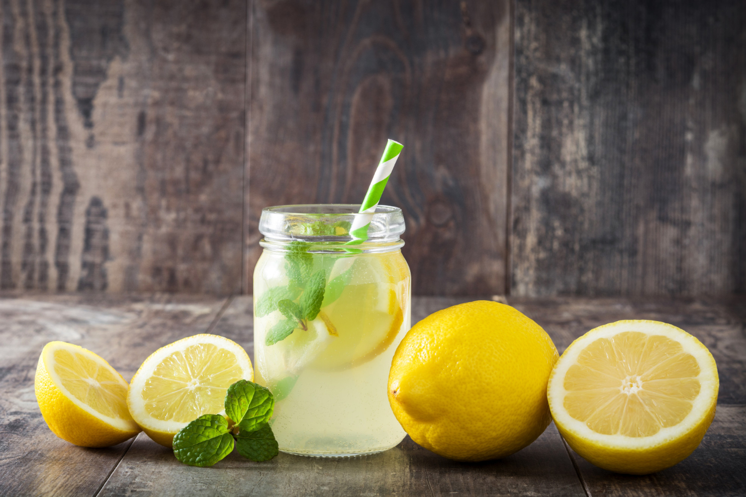 A refreshing glass of lemon smoothie garnished with a lemon slice and mint leaves.